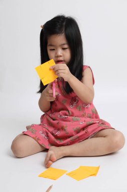 Kağıdı kesmek için makas kullanan Asyalı kız..