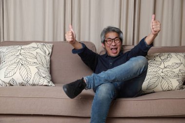 Oturma odasındaki kanepede oturan kıdemli Asyalı adam..