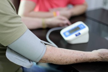 Yaşlı Asyalı adam evde kan basıncını ölçüyor..