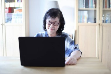 Dizüstü bilgisayar kullanan yaşlı Asyalı kadın..