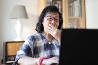 Dizüstü bilgisayar kullanan yaşlı Asyalı kadın..