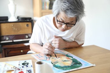 Stüdyoda resim yapan Asyalı adam..