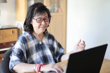 Dizüstü bilgisayar kullanan yaşlı Asyalı kadın..