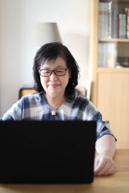 Dizüstü bilgisayar kullanan yaşlı Asyalı kadın..