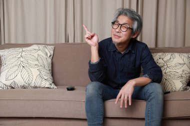 Oturma odasındaki kanepede oturan kıdemli Asyalı adam..