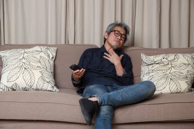 Oturma odasındaki kanepede oturan kıdemli Asyalı adam..