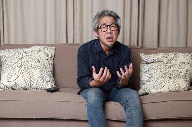 Oturma odasındaki kanepede oturan kıdemli Asyalı adam..