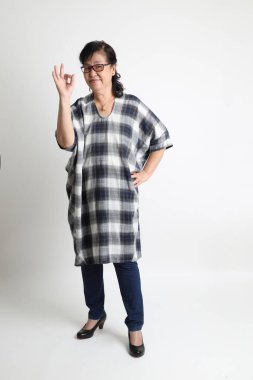 Beyaz arka planda duran yaşlı Asyalı kadın..