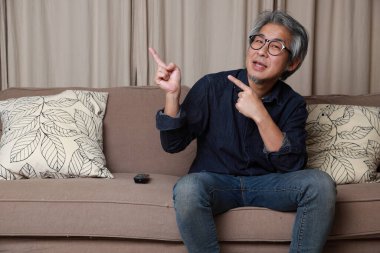 Oturma odasındaki kanepede oturan kıdemli Asyalı adam..