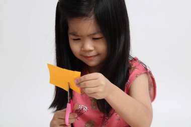 Kağıdı kesmek için makas kullanan Asyalı kız..