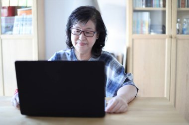 Dizüstü bilgisayar kullanan yaşlı Asyalı kadın..