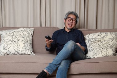 Oturma odasındaki kanepede oturan kıdemli Asyalı adam..