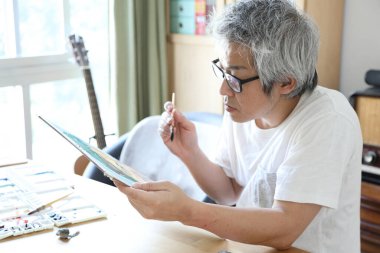 Stüdyoda resim yapan Asyalı adam..