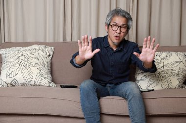 Oturma odasındaki kanepede oturan kıdemli Asyalı adam..