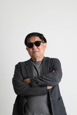 Beyaz arka planda güneş gözlüklü Asyalı son sınıf öğrencisi..