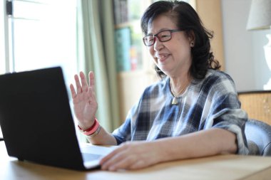 Dizüstü bilgisayar kullanan yaşlı Asyalı kadın..