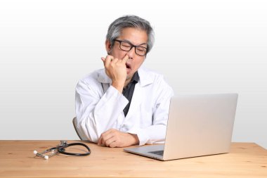 Dizüstü bilgisayarla oturan kıdemli Asyalı doktor..