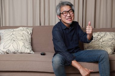 Oturma odasındaki kanepede oturan kıdemli Asyalı adam..