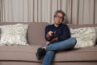 Oturma odasındaki kanepede oturan kıdemli Asyalı adam..