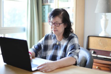 Dizüstü bilgisayar kullanan yaşlı Asyalı kadın..