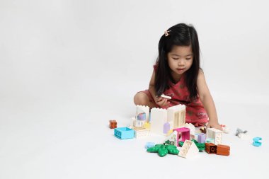 Beyaz arka planda oyuncak oynayan Asyalı kız..