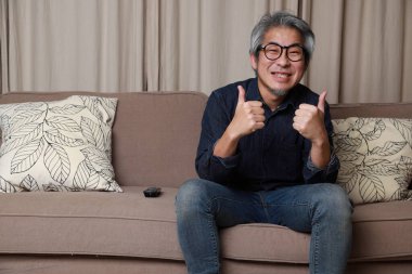 Oturma odasındaki kanepede oturan kıdemli Asyalı adam..