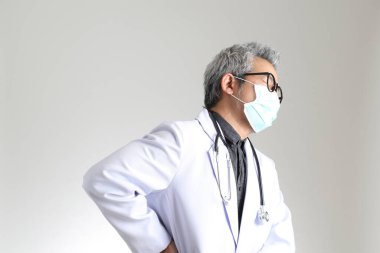 Beyaz arka planda maskesi olan kıdemli Asyalı doktor..