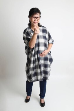 Beyaz arka planda duran yaşlı Asyalı kadın..