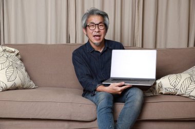 Oturma odasındaki kanepede oturan kıdemli Asyalı adam..