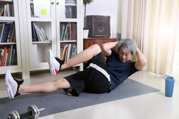 那个在客厅里做运动的亚洲老人 — 图库照片