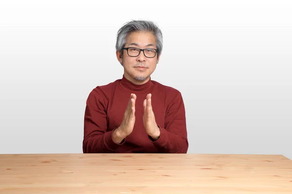 Beyaz Arka Planda Masada Oturan Kıdemli Asyalı Adam — Stok fotoğraf