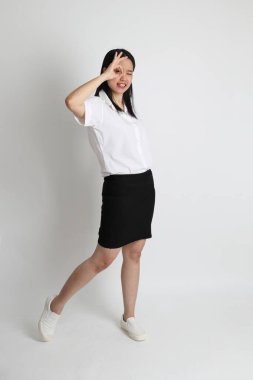 Üniversite üniformalı Asyalı kız beyaz arka planda duruyor..