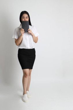 Üniversite üniformalı Asyalı kız beyaz arka planda duruyor..