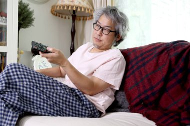 Asyalı adam evinde televizyon izliyor..