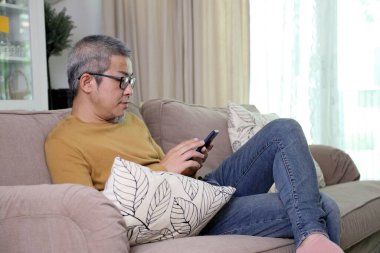 Asyalı adam oturma odasında dinleniyor..