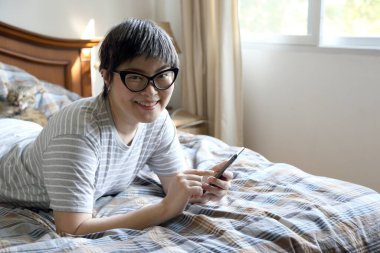 Yatakta akıllı telefon kullanan Asyalı kadın..