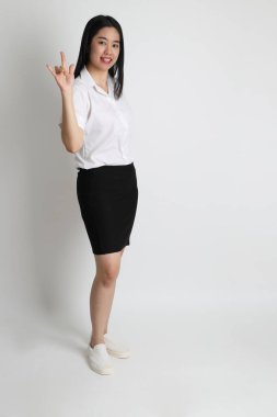 Üniversite üniformalı Asyalı kız beyaz arka planda duruyor..