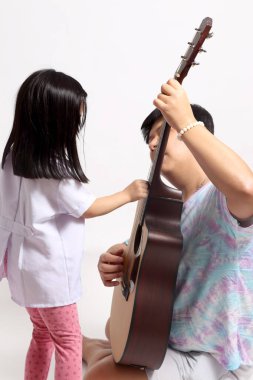 Asyalı adam kızına gitar çalmayı öğretiyor..