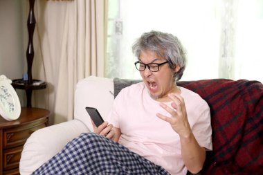 Oturma odasında akıllı telefon kullanan Asyalı adam..