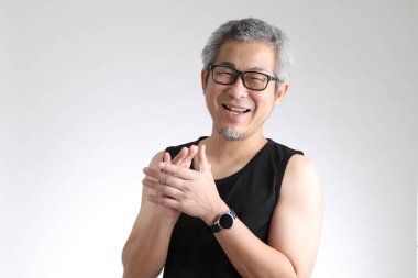 Beyaz arka planda duran spor üniformalı yaşlı Asyalı adam..