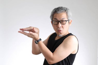 Beyaz arka planda duran spor üniformalı yaşlı Asyalı adam..