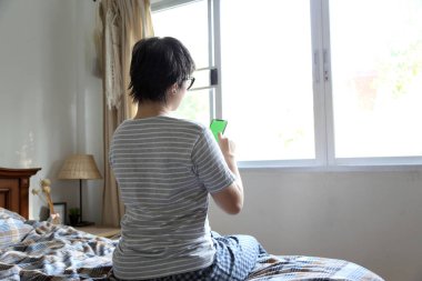 Yatakta akıllı telefon kullanan Asyalı kadın..