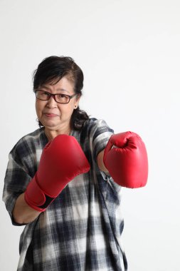 Beyaz arka planda duran yaşlı Asyalı kadın..