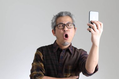 Beyaz arka planda duran kıdemli Asyalı adam.