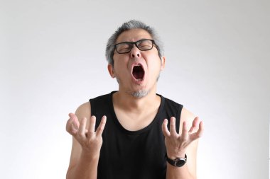 Beyaz arka planda duran spor üniformalı yaşlı Asyalı adam..