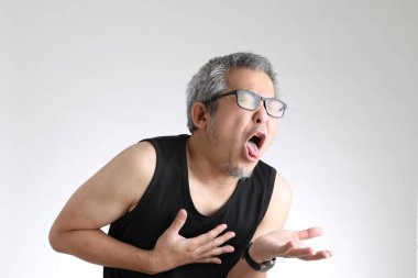 Beyaz arka planda duran spor üniformalı yaşlı Asyalı adam..