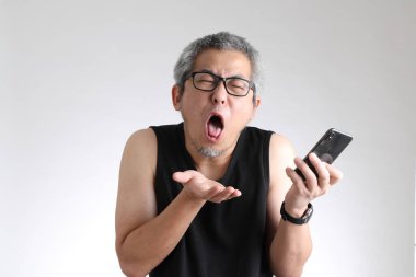 Beyaz arka planda duran spor üniformalı yaşlı Asyalı adam..