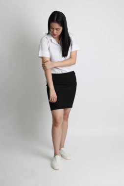 Üniversite üniformalı Asyalı kız beyaz arka planda duruyor..