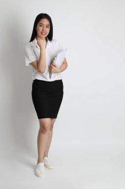 Üniversite üniformalı Asyalı kız beyaz arka planda duruyor..