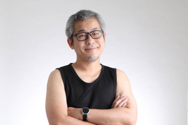 Beyaz arka planda duran spor üniformalı yaşlı Asyalı adam..